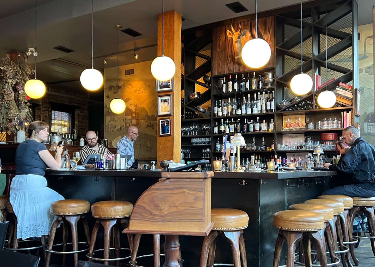 People sit on leather stools around the bar at Bistrot L'Stage in Victoria