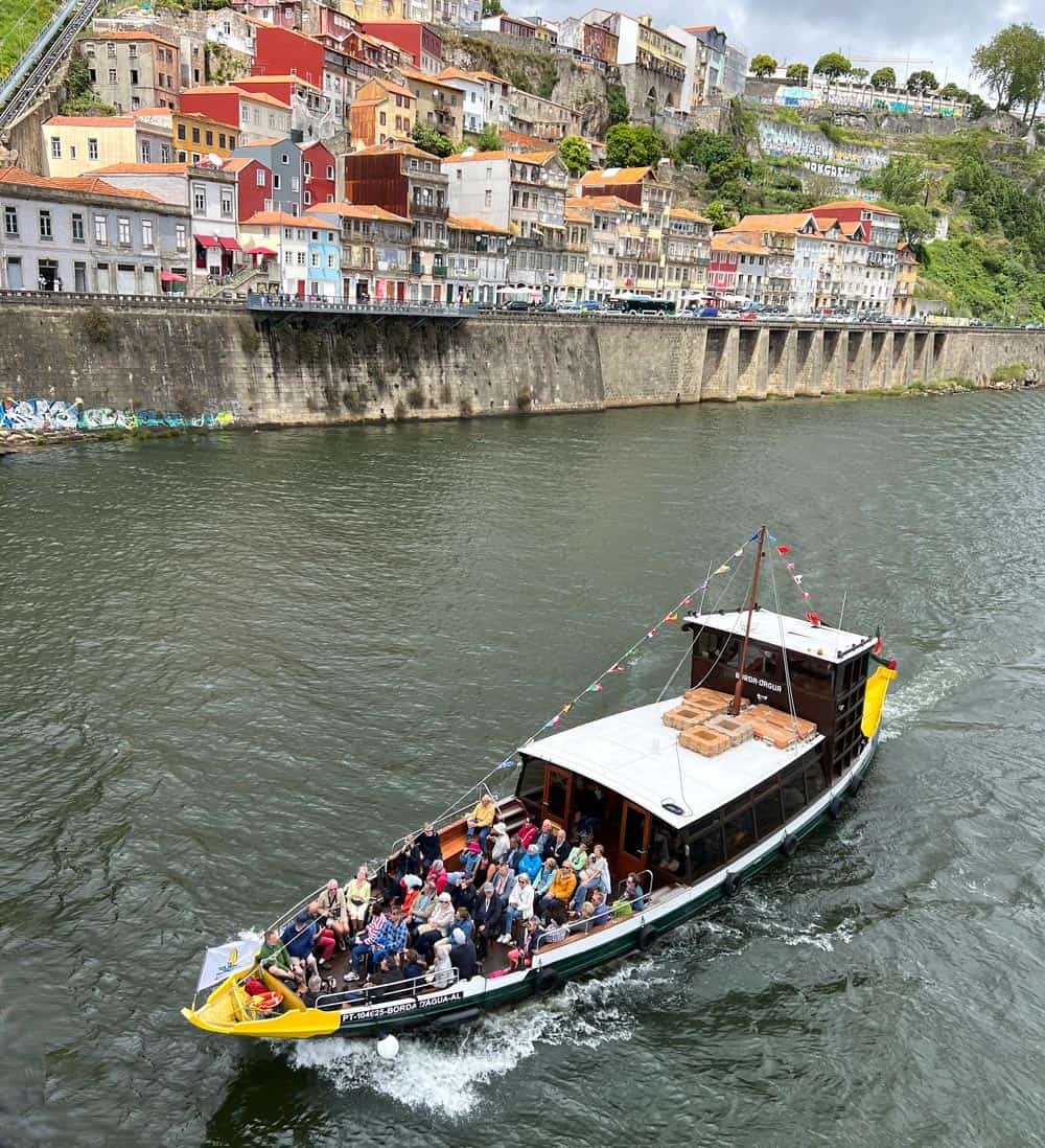 Visitors sit at the front of a rabelo boat on the Douro River in Porto.