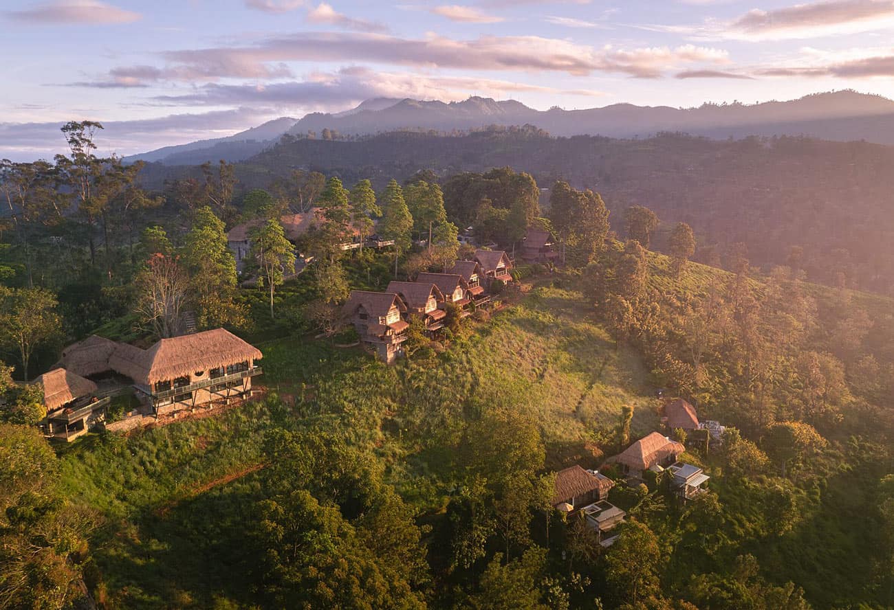 Thatched-roof chalets on hillside against a purple and pink sky