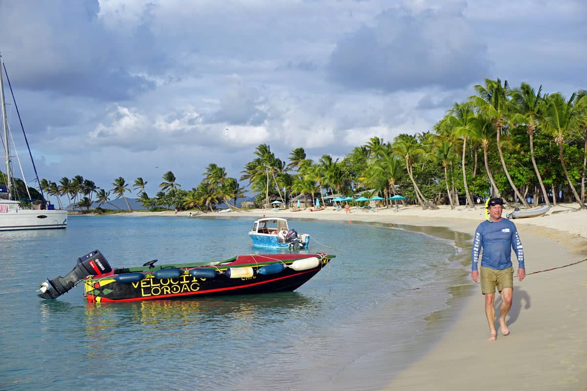 Gold sand beach, framed by palm trees, with a red boat anchored in the water