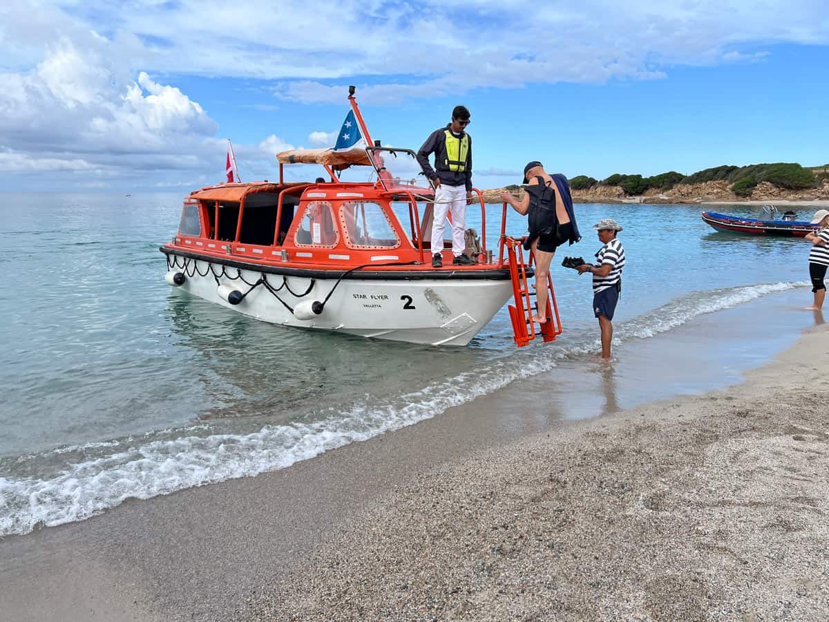 A guest climbs down the tender’s ladder for a “wet landing” at remote Plage Saint-Antoine.