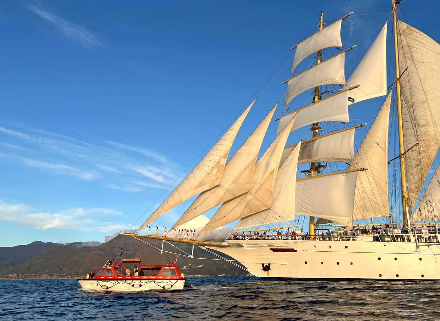 A photo-safari tender passes the Star Flyer under full sail.