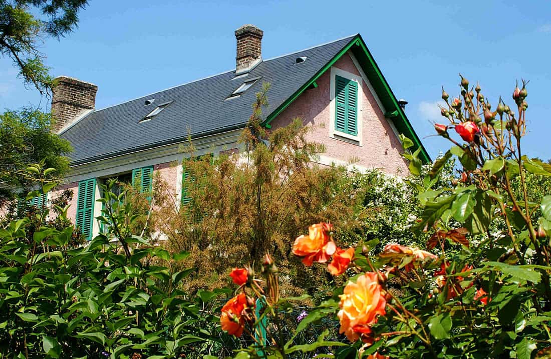 Roses bloom in front of the pink Claude Monet house in Giverny.