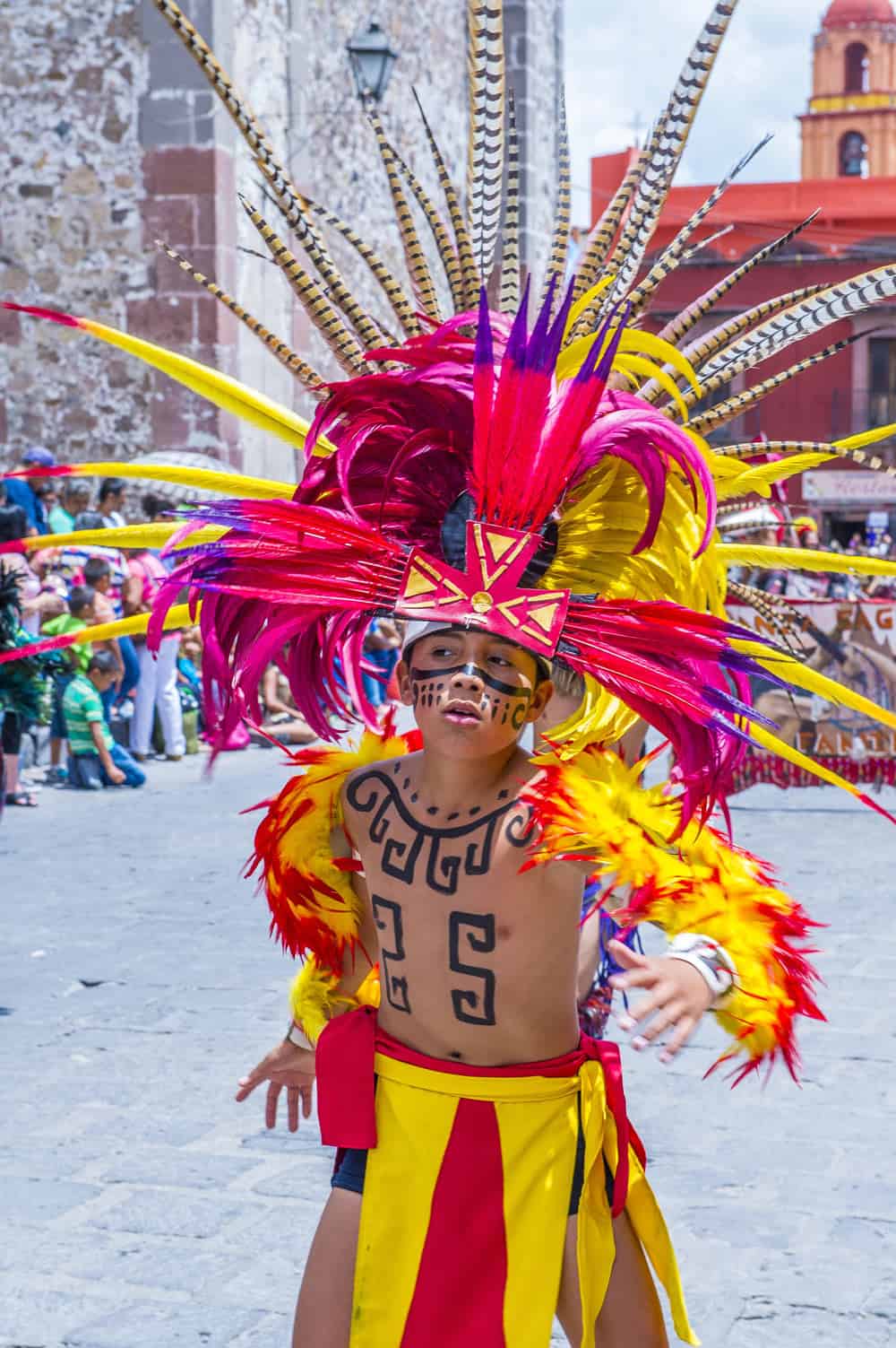 Young boy in pink and yellow feather costume at the Festival Valle de Maiz in San Miguel de Allende