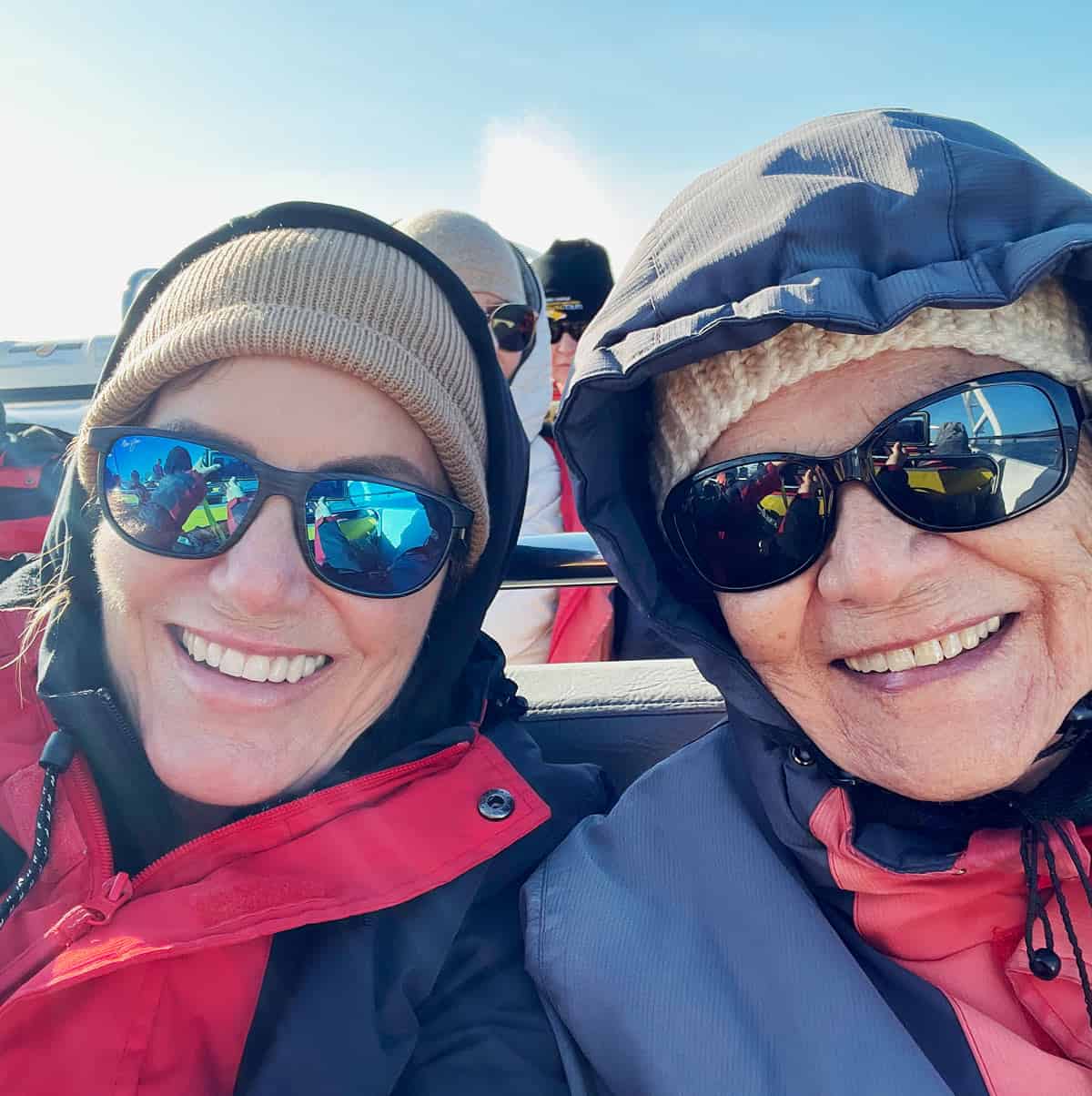 Two women dressed in thick jackets and hats on a whale watching boat in Victoria