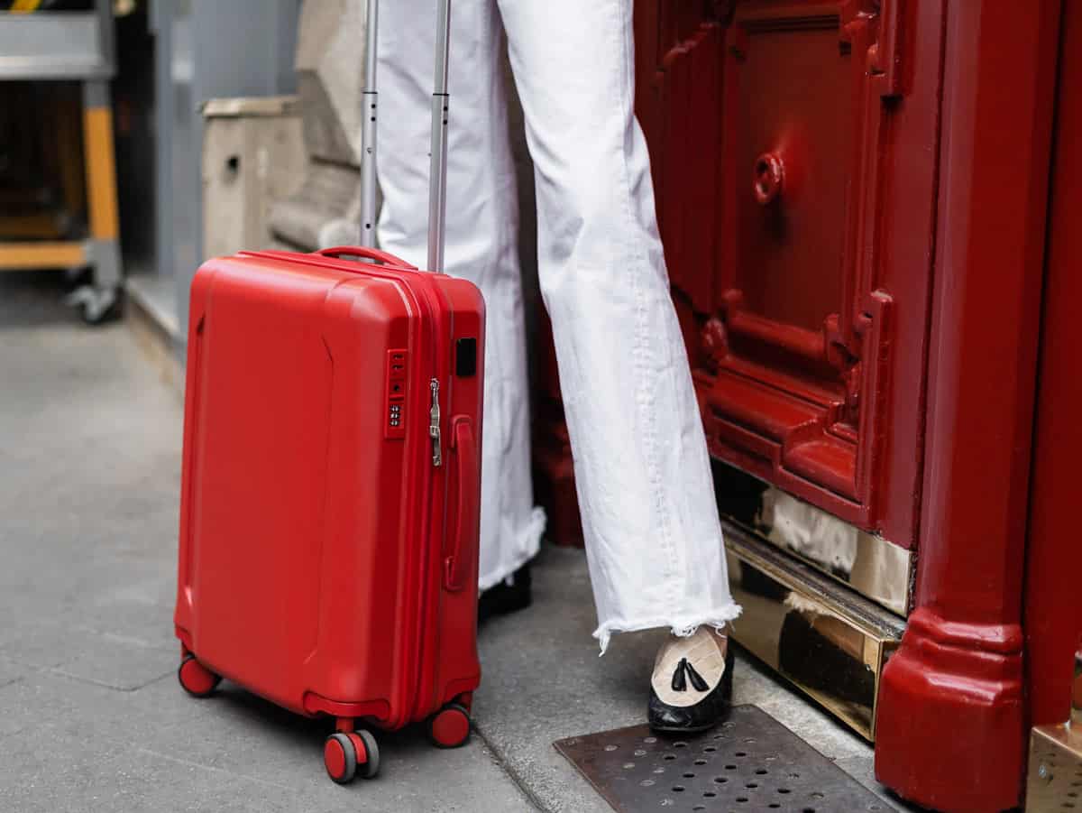 Woman in white jeans with a small red suitcase in Paris