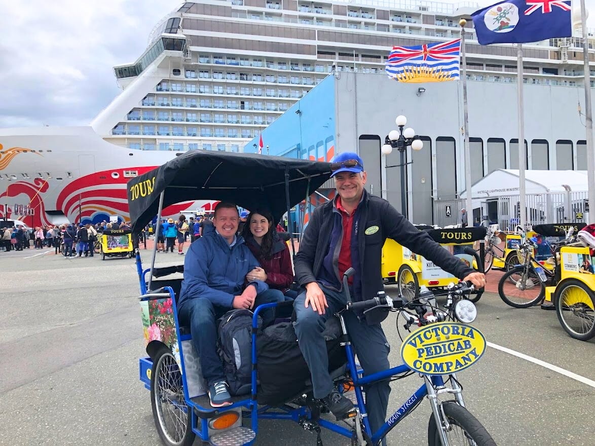 Smiling couple in a Victoria pedicab at the cruise terminal