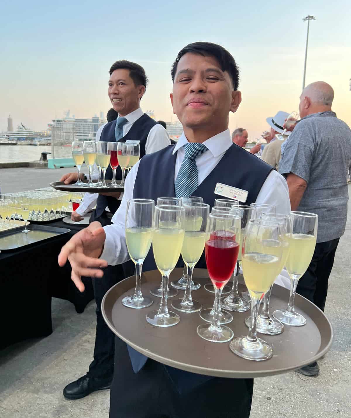 Ship crew with trays of limoncello spritz and cranberry cocktails