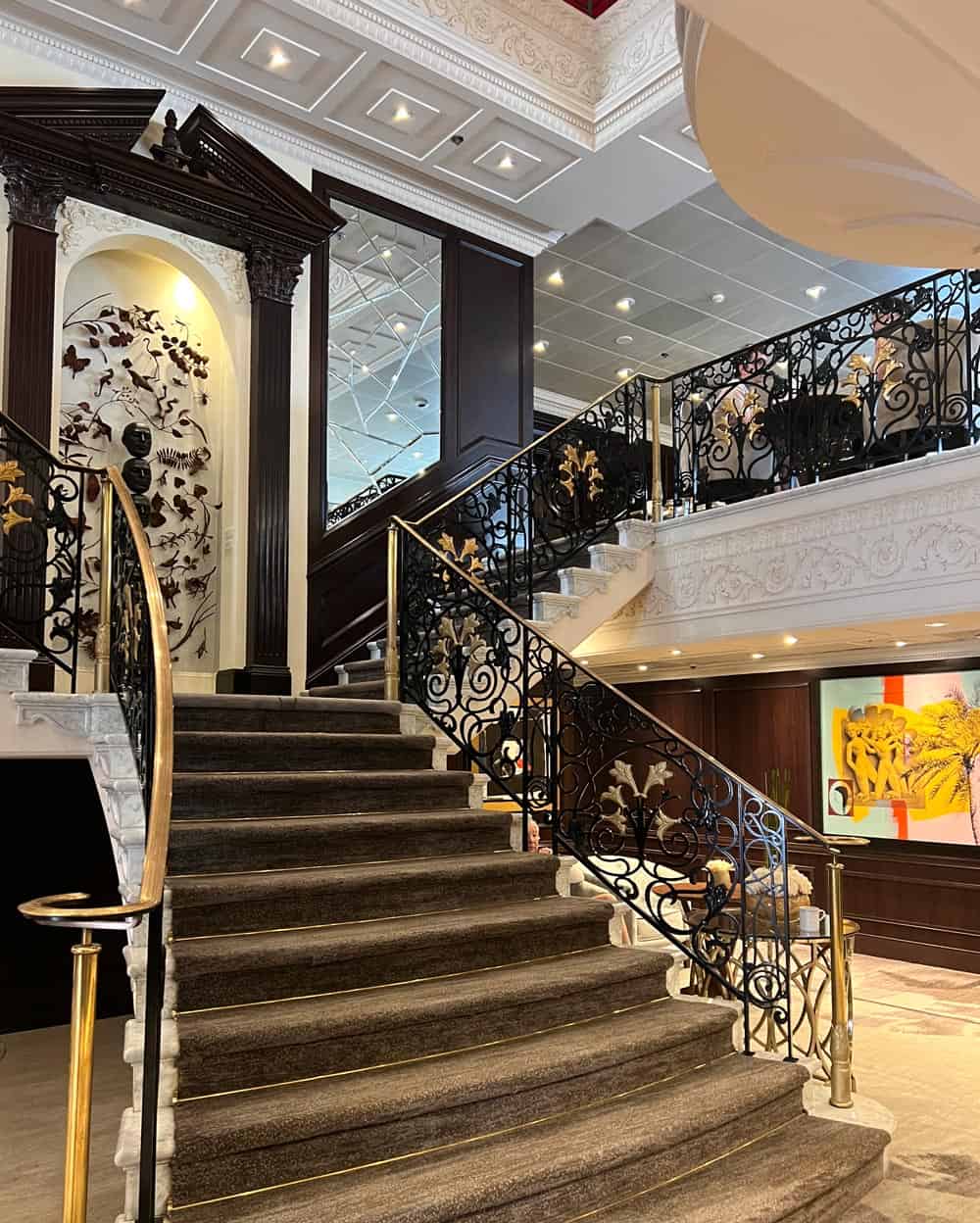 The grand staircase on Azamara Quest features ornate wrought-iron railings, dark wood accents and a touch of old-world elegance.