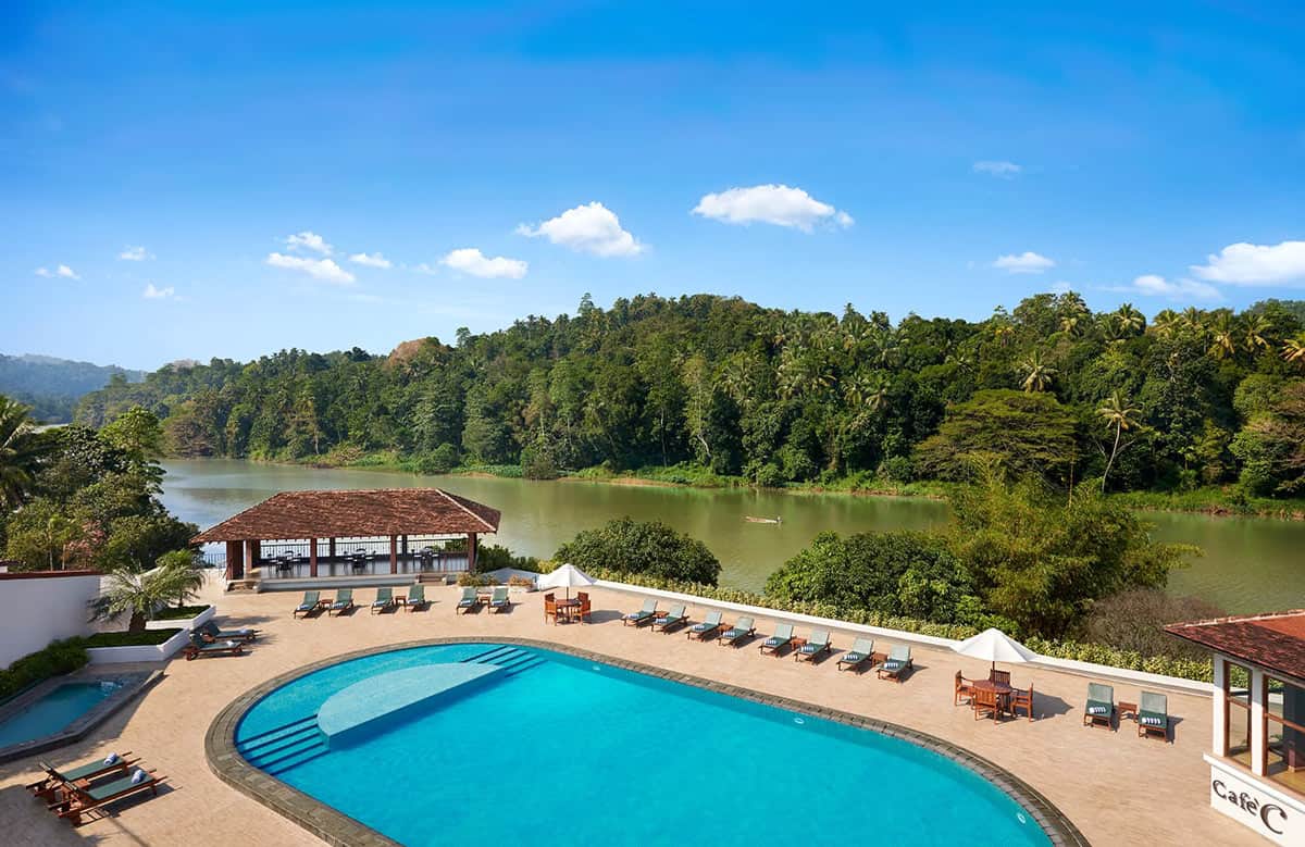Outdoor oval blue swimming pool at Cinnamon Citadel Kandy overlooking the Mahaweli River and lush tropical forest