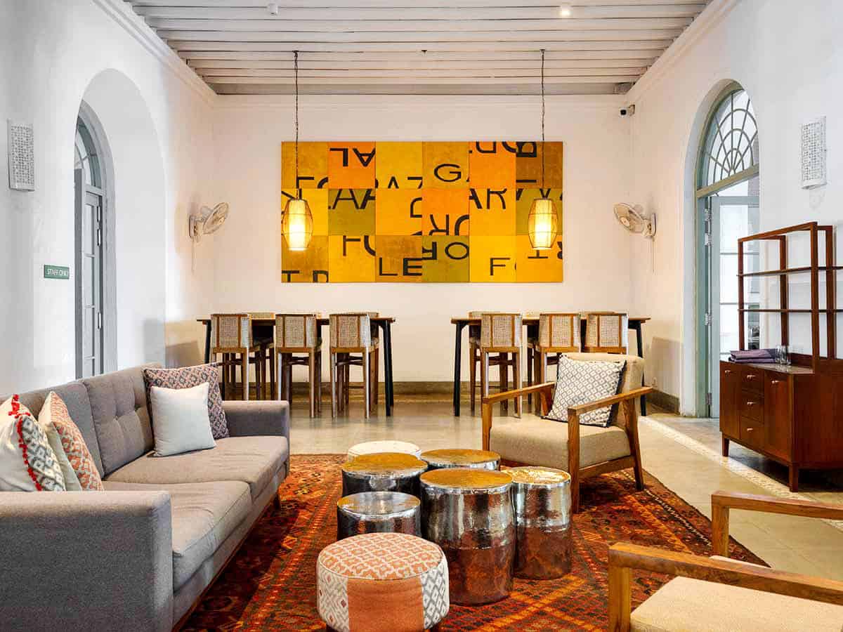 Contemporary lounge at Fort Bazaar in Galle Fort with orange-colored modern artwork, wooden furniture and arched windows