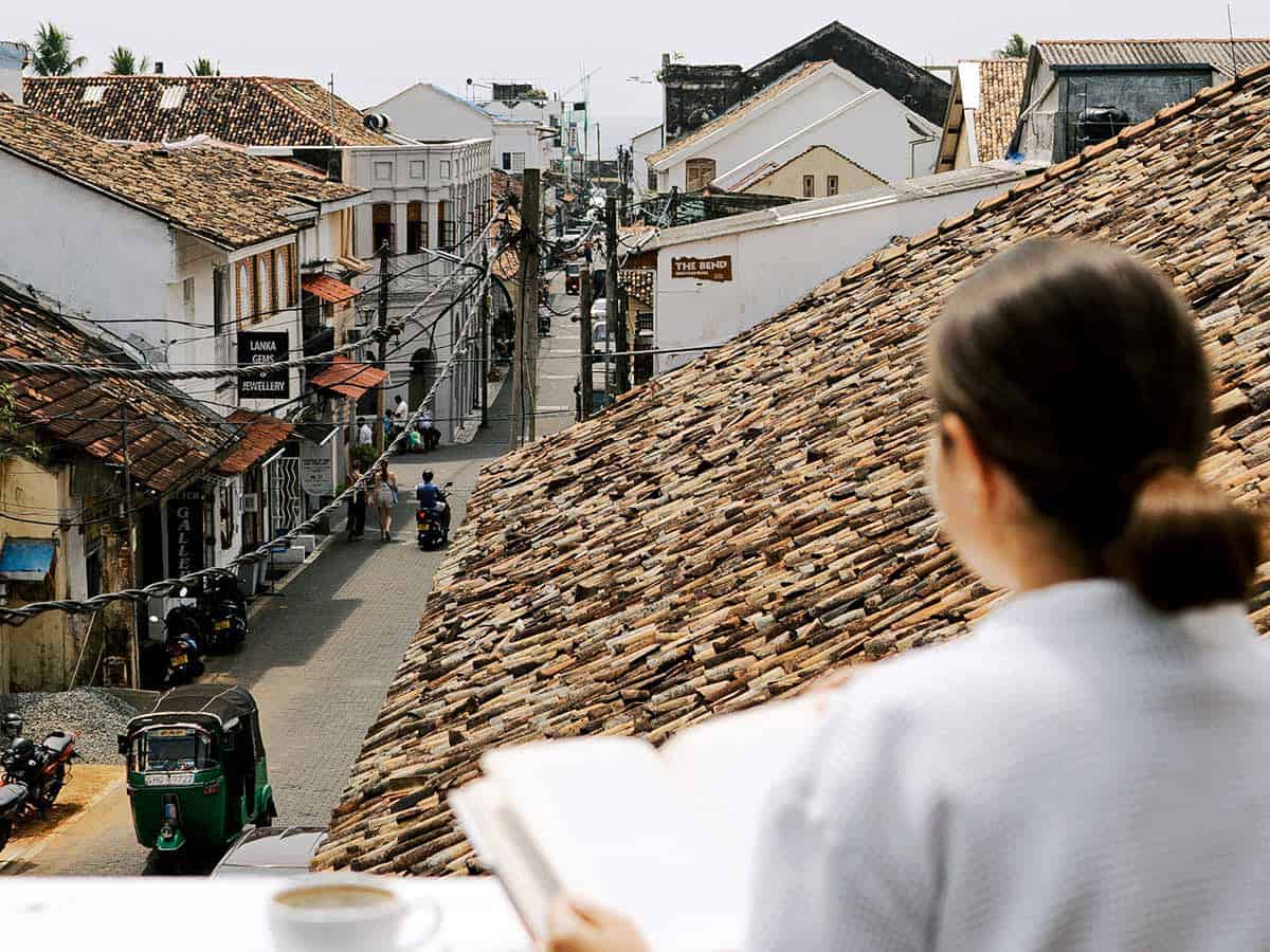 A woman looks out over over the tiled rooftops and narrow streets of Galle Fort from Fort Bazaar.