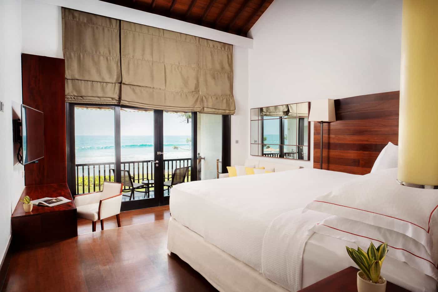 An Ocean View Room at The Fortress Resort, with polished warm wood floors and furniture and a king bed draped in white linens