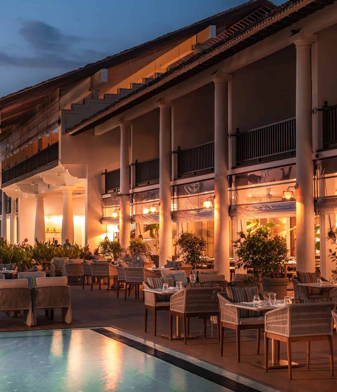 Poolside restaurant and outdoor dining terrace at The Fortress Resort & Spa, softly lit at night