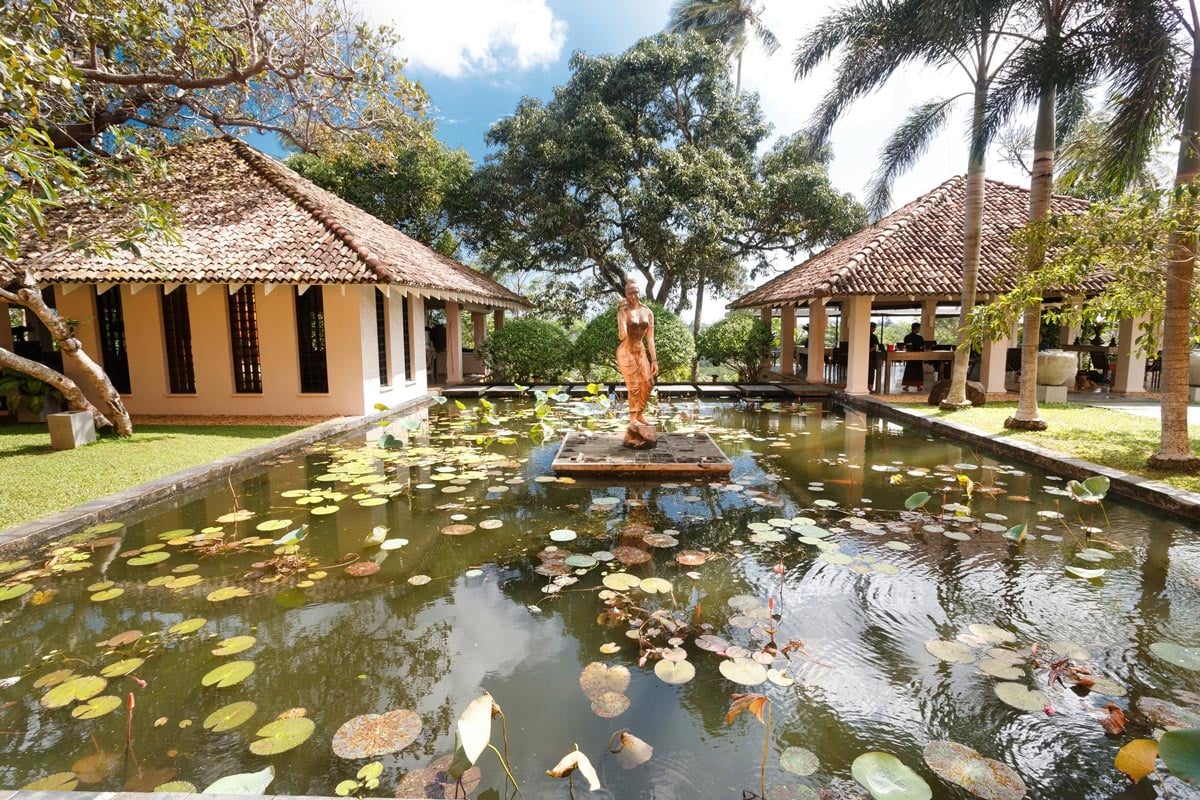 Lily pond with a statue, tropical gardens and tiled-roof pavilions at Kahanda Kanda in Sri Lanka