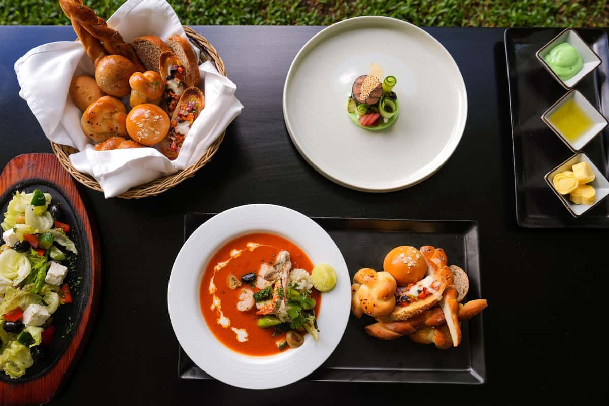 Red seafood soup, a wooden bowl of salad, assorted breads and more for dinner at Kings Pavilion Luxury Hotel