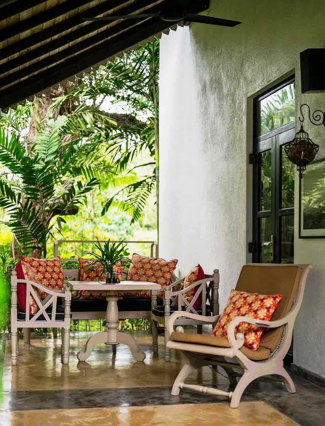 Covered veranda with colonial-style furniture with orange cushions