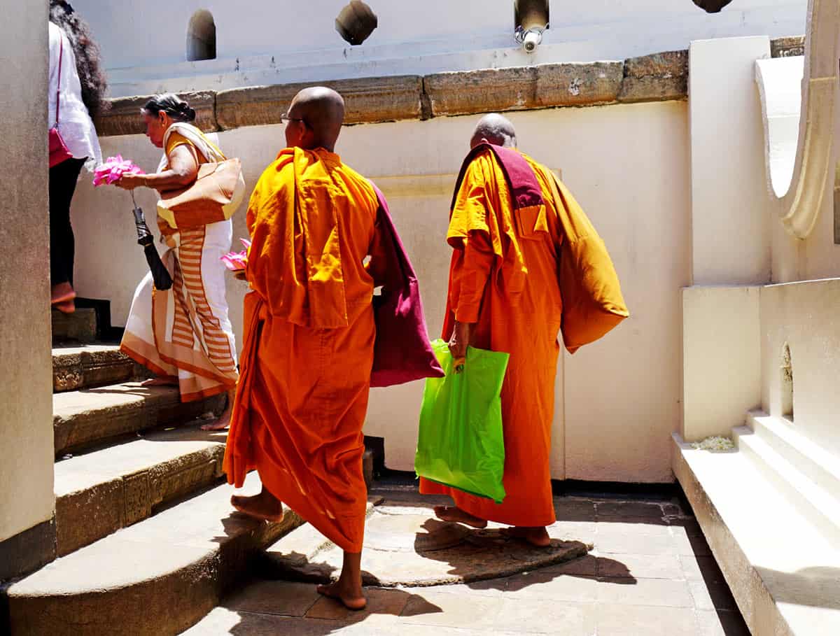 Orange-robed Buddhist monks make their way through Kandy’s Temple of the Tooth complex.