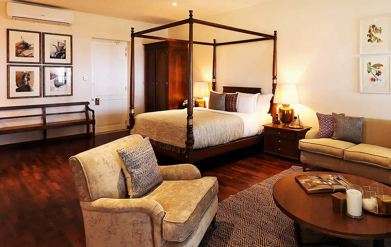Bungalow Estate with a dark wood four-poster bed, sitting area and polished wood floors