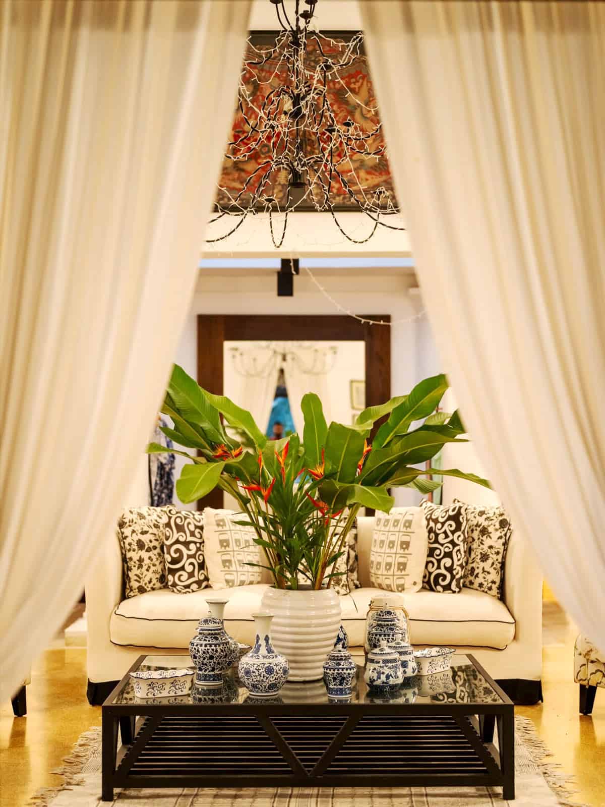 Elegant lounge at Why House with blue-and-white ceramics, tropical flowers and flowing white curtains