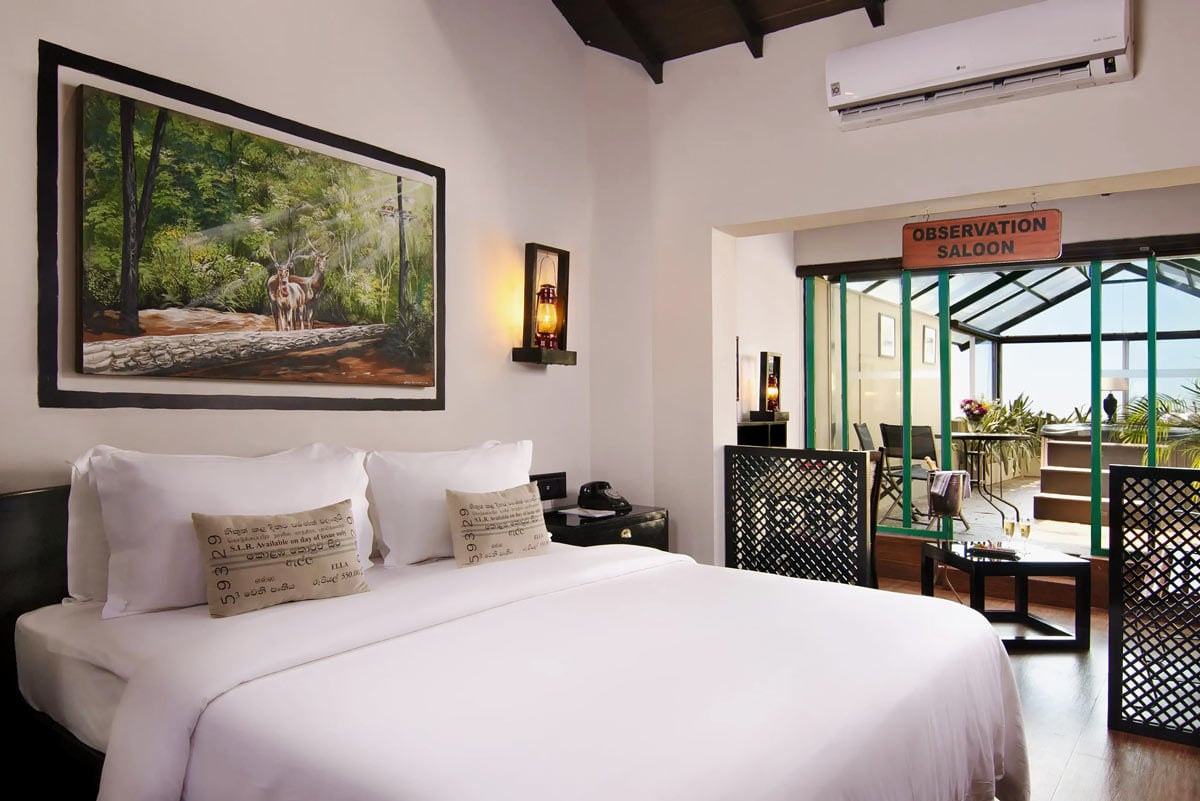 Junior Suite at EKHO Ella with bed covered in white linens, and private Jacuzzi in a glass nook overlooking the mountains