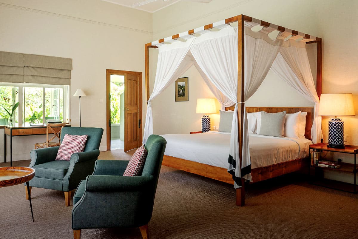 Spacious Nine Skies bedroom with a four-poster king bed, sitting area and modern tea-country decor