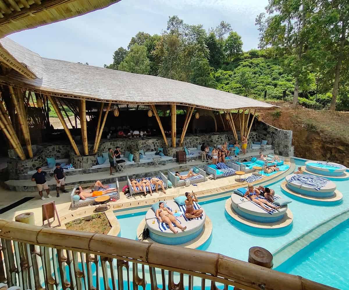 Guests lounge on white daybeds set on raised circular platforms in the pool at Ravana Pool Club at 98 Acres Resort.