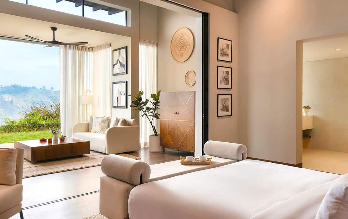 Spacious modern villa bedroom at Uga Ghiri in Ella, with a king bed, sitting area, wood floors and mountain views through floor-to-ceiling windows